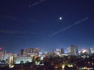 Moon over the Night Skyline – Aerial at night with a bright moon above city lights.