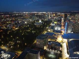 Downtown Lights from Above – Aerial night view of downtown with blue-lit tower and light-lined streets.