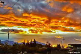 Fiery Sunset Over Treeline – Fiery sunset over a tree line. Oct 13, 2019. John England.
